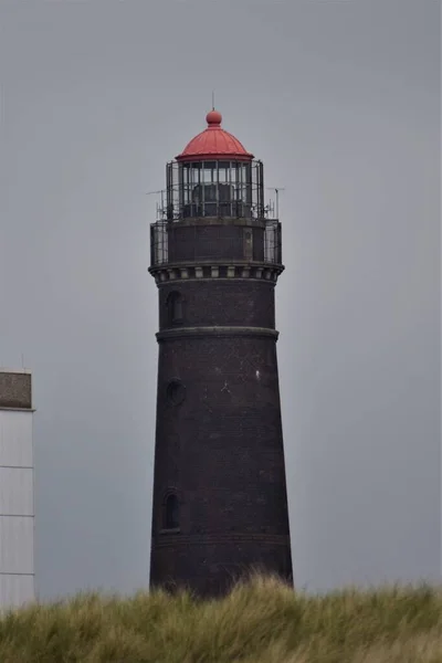 Een baksteen vuurtoren tegen een grijze lucht — Stockfoto