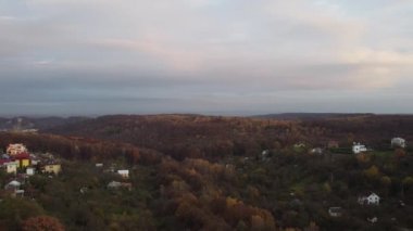 Binaların ve ormanın üzerinde uçan bir İHA 'nın hava görüntüsü.