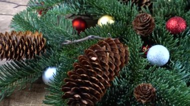 Eski ahşap bir tahtanın üzerinde koni ve Noel topları olan bebek nobilis dalları.