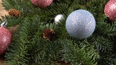 Eski ahşap bir tahtanın üzerinde koni ve Noel topları olan bebek nobilis dalları.