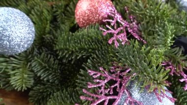 Eski ahşap bir tahtanın üzerinde koni ve Noel topları olan bebek nobilis dalları.