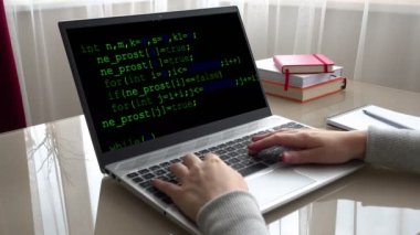 Ekrandaki kaynak kodu. Ev işlerinde çalışan klavyede çalışan kız..