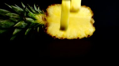 Falling juicy pieces of pineapple on a black background. Slow motion.