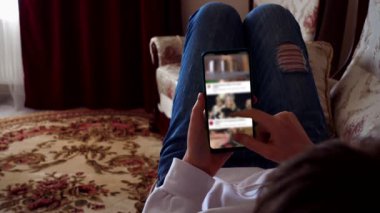 Bir genç akıllı telefondan eğlence videosu izler..