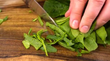 Aşçı ahşap bir tahta üzerinde ıspanak yaprakları keser..