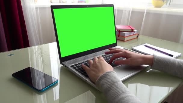 自宅のオフィスでキーボードを手に働く少女 画面は緑の背景です — ストック動画