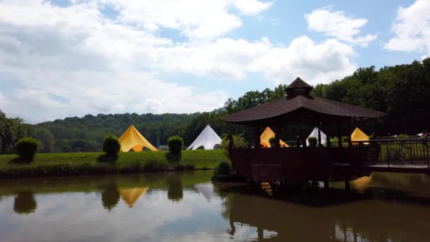 森林的湖泊和帐篷在森林和云彩的背景下 湖心区的木制露台 — 图库视频影像
