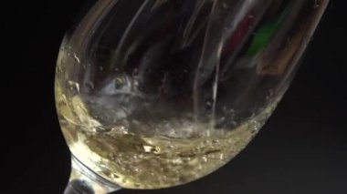 Şarap siyah arka planda bir bardağa dökülür. Yavaş çekim.