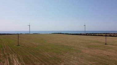 Rüzgar türbini ve tarımsal alanların üzerinde uçan bir dron görüntüsü. Denizin arka planında yel değirmenleri. Yel değirmeni. Rüzgar çiftliği.
