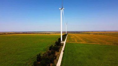 Rüzgar türbini ve tarımsal alanların üzerinde uçan bir dron görüntüsü. Ayçiçeği tarlası. Yel değirmeni. Rüzgar çiftliği.