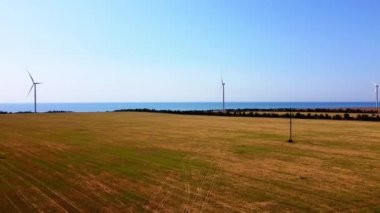Rüzgar türbini ve tarımsal alanların üzerinde uçan bir dron görüntüsü. Denizin arka planında yel değirmenleri. Yel değirmeni. Rüzgar çiftliği.