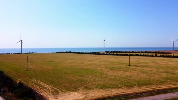 風力タービンと農業分野上の飛行の空中ドローンビュー 海の背景に風車 風車だ 風力発電所 — ストック動画