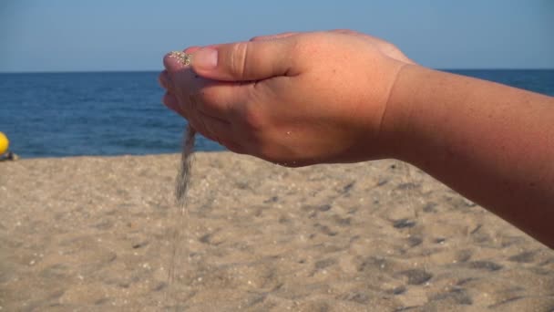 砂は海を背景に女性の手から落ちる — ストック動画
