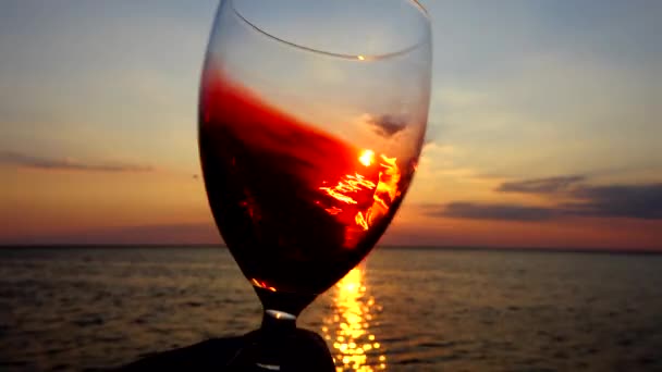酒杯中的酒在日落的背景下洒在海面上 慢动作 — 图库视频影像
