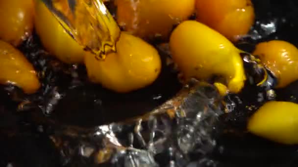 黄色のチェリートマトを水に落とす トマトを洗う 黒を背景に スローモーション — ストック動画
