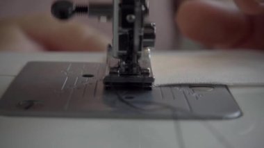 Kumaş ve iplikle dikiş makinesi, yakın plan. Yavaş çekim.