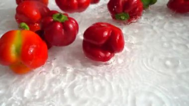 Çan tatlı biberleri suya düşüyor. Yavaş çekim.