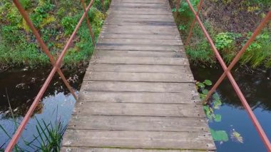 Göletin üzerinde metal parmaklıklar olan tahta bir köprü..