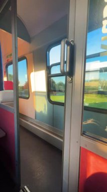 Tren yolculuğu. Akşam güneşiyle aydınlanan bir tren vagonunun duvarında küçük bir çocuğu olan bir annenin gölgesi. Dikey video.