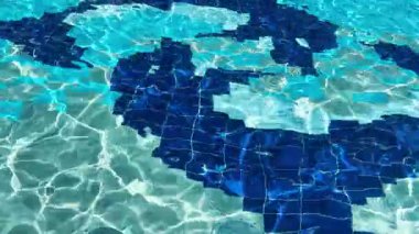 Açık havuz alanında. Gün ışığı berrak mavi sularda parlar ve dalgalanır..