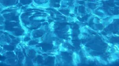 Açık havuz alanında. Gün ışığı berrak mavi sularda parlar ve dalgalanır..