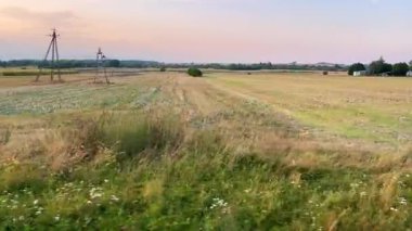 Yaz sonlarında gün batımında Polonya 'daki kırsal bir arazinin ve kırsal bir arazinin tren penceresinden görüntüsü.