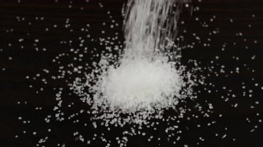 Beyaz şeker kristalleri koyu kahverengi ahşap bir yüzeye serpilmiştir. Bir yığın şeker, bir sürü şeker..