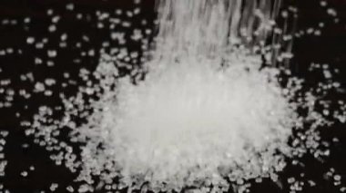 Beyaz şeker kristalleri koyu kahverengi ahşap bir yüzeye serpilmiştir. Bir yığın şeker, bir sürü şeker..