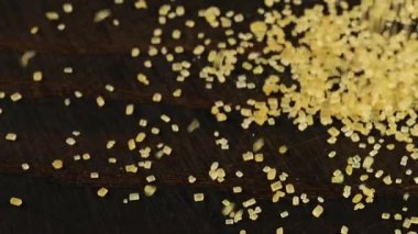 Kahverengi şeker kristalleri koyu kahverengi ahşap bir yüzeye serpilmiştir..