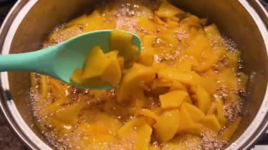 Ayva reçeli büyük bir tencerede kaynıyor. Silikon spatulayla reçeli karıştırıyorum..