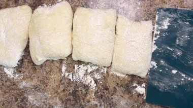 Çiğ maya hamuru parçaları, mutfak spatulası kullanılarak iş yüzeyinden taşınır..