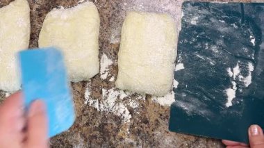 Çiğ maya hamuru parçaları, mutfak spatulası kullanılarak iş yüzeyinden taşınır..