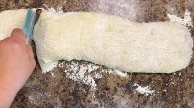 Uzun bir maya hamuru parçası ciabatta pişirmek için bir spatula kullanılarak porsiyonlara bölünür..