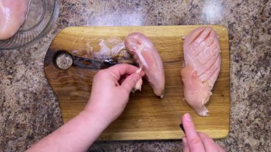 Çiğ tavuk göğsü terbiye sürecini geliştirmek ve daha fazla pişirmek için bıçakla çizilir. Tahta meşe kesme tahtası..