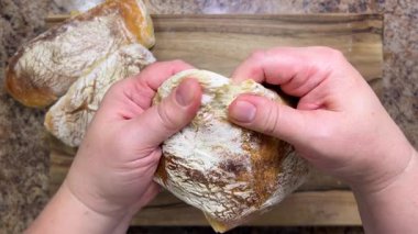 Taze pişmiş, lezzetli ev yapımı ciabatta elle ikiye bölünmüş. Ciabatta ceviz ağacından kesme tahtasında.