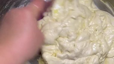 Metal bir kasenin kenarlarından spatulayla maya mayası kazıyın. Evde hamur mayası yapma süreci.