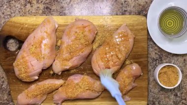 Baharatları silikon fırça ve bitkisel yağ kullanarak tavuk göğsüne eşit olarak yay. Tahta meşe kesme tahtası..