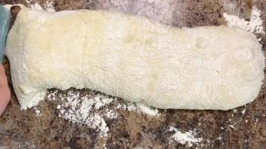 Uzun bir maya hamuru parçası ciabatta pişirmek için bir spatula kullanılarak porsiyonlara bölünür..