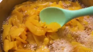 Ayva reçeli büyük bir tencerede kaynıyor. Silikon spatulayla reçeli karıştırıyorum..