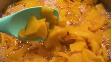 Ayva reçeli büyük bir tencerede kaynıyor. Silikon spatulayla reçeli karıştırıyorum..