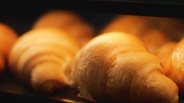 Taze pişmiş altın kruvasanlar sergileniyor. Yakın plan çekimleri, onların tuhaf dokularını ve iştah açıcı görüntülerini vurguluyor. Bu görüntüler gıda projeleri ya da fırın reklamları için mükemmel..