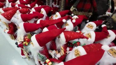 Bir alışveriş merkezinde sergilenen birçok Noel Baba oyuncağını yakından çek. Bir perakende mağazasında satılık Noel süslemeleri. Geleneksel Noel Baba figürleri için tatil sezonu alışverişi.