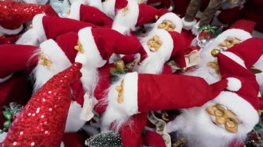 Bir alışveriş merkezinde sergilenen birçok Noel Baba oyuncağını yakından çek. Bir perakende mağazasında satılık Noel süslemeleri. Geleneksel Noel Baba figürleri için tatil sezonu alışverişi.