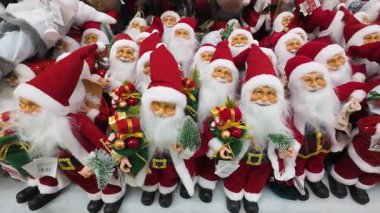 Bir alışveriş merkezinde sergilenen birçok Noel Baba oyuncağını yakından çek. Bir perakende mağazasında satılık Noel süslemeleri. Geleneksel Noel Baba figürleri için tatil sezonu alışverişi.