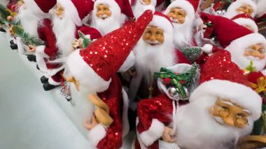 Bir alışveriş merkezinde sergilenen birçok Noel Baba oyuncağını yakından çek. Bir perakende mağazasında satılık Noel süslemeleri. Geleneksel Noel Baba figürleri için tatil sezonu alışverişi.