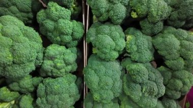 Taze yeşil brokoli kafaları, süpermarket ortamında satılmaya hazır ahşap sandıklarda güzelce düzenlenir. Bu yakın çekim sağlıklı sebzelerin dokusunu ve canlı rengini vurgular..