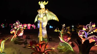 LVIV, UKRAINE - Ocak 06, 2026: Karlı bir parkta aydınlatılmış savaşçı kraliçe heykeli. Renkli fener figürleri büyülü bir kış harikalar diyarı gösterisi yaratıyor..