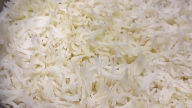 Taze pişmiş beyaz basmati pilavı tencerede pişiyor. Sıcak, kabarık tanecikleri yakından çek, yemek için mükemmel..