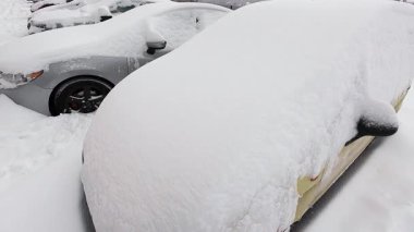 Yoğun bir kar fırtınasından sonra arabalar tamamen karla kaplandı. Terk edilmiş bir otoparkta zorlu hava koşulları ve soğuk hava sergileniyor..