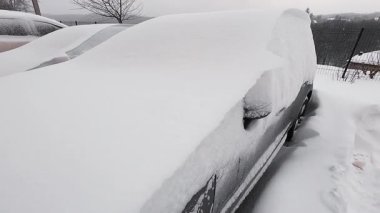 Yoğun bir kar fırtınasından sonra arabalar tamamen karla kaplandı. Terk edilmiş bir otoparkta zorlu hava koşulları ve soğuk hava sergileniyor..
